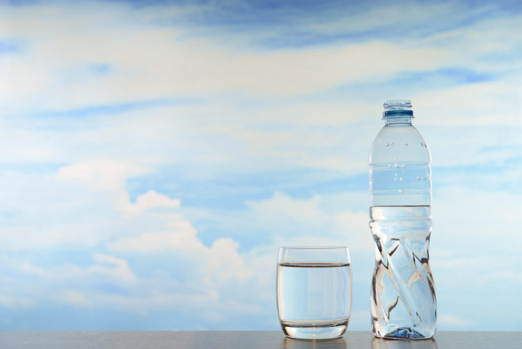 Fresh and clean drinking water in bottle and glass on sky background