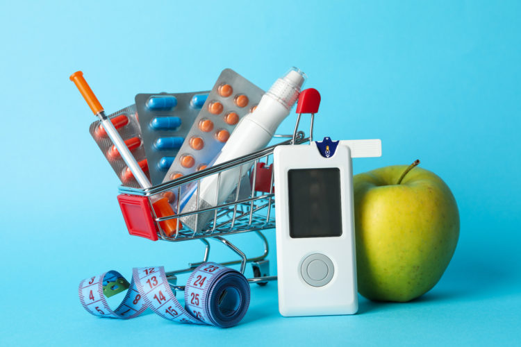 Shopping cart with diabetes accessories on blue background