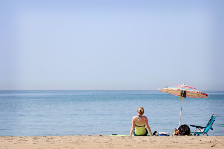 woman-sitting-at-the-beach-watching-the-sea-VDWSVQ3