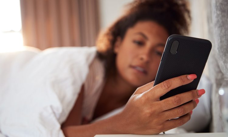 young-woman-checks-mobile-phone-from-bed